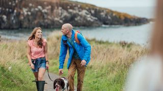 Man and woman walking a brown and white dog