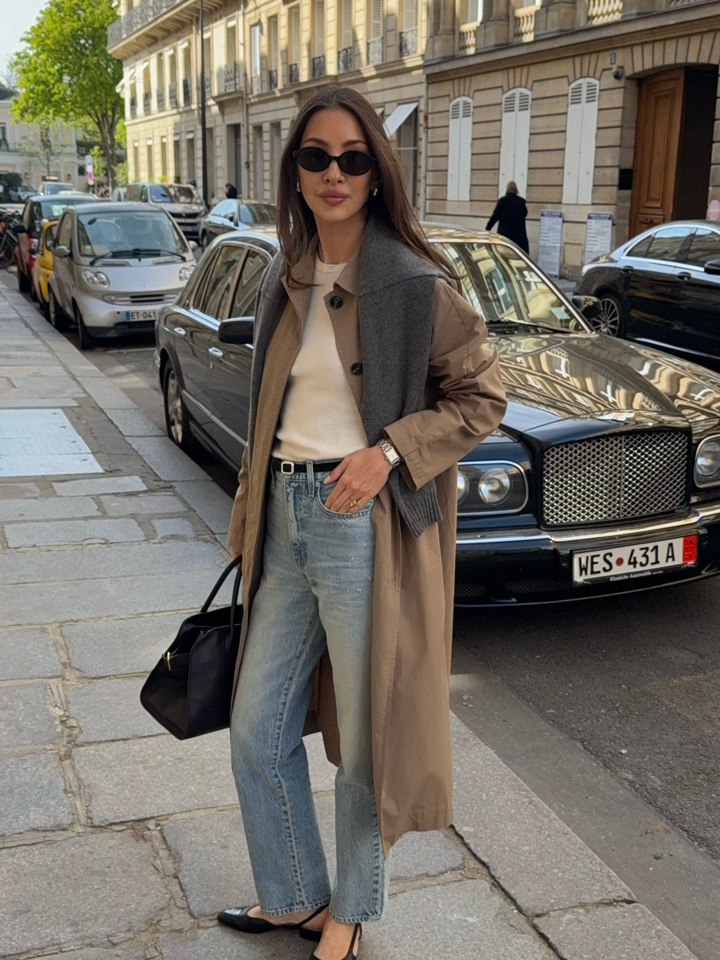 @fakerstrom wearing a trench coat, white T-shirt, high-waisted jeans, and flat slingbacks.