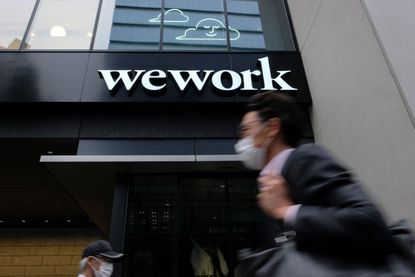 A man walks past the logo of WeWork in Tokyo on May 18, 2020