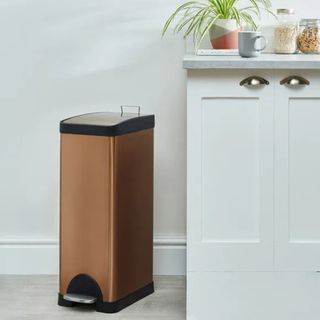 A slimline copper colored foot pedal operated kitchen bin by Dunelm