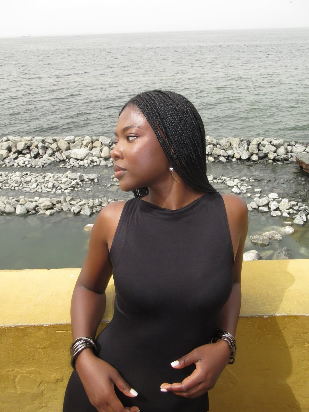 A woman in a black dress leaning against a ledge.