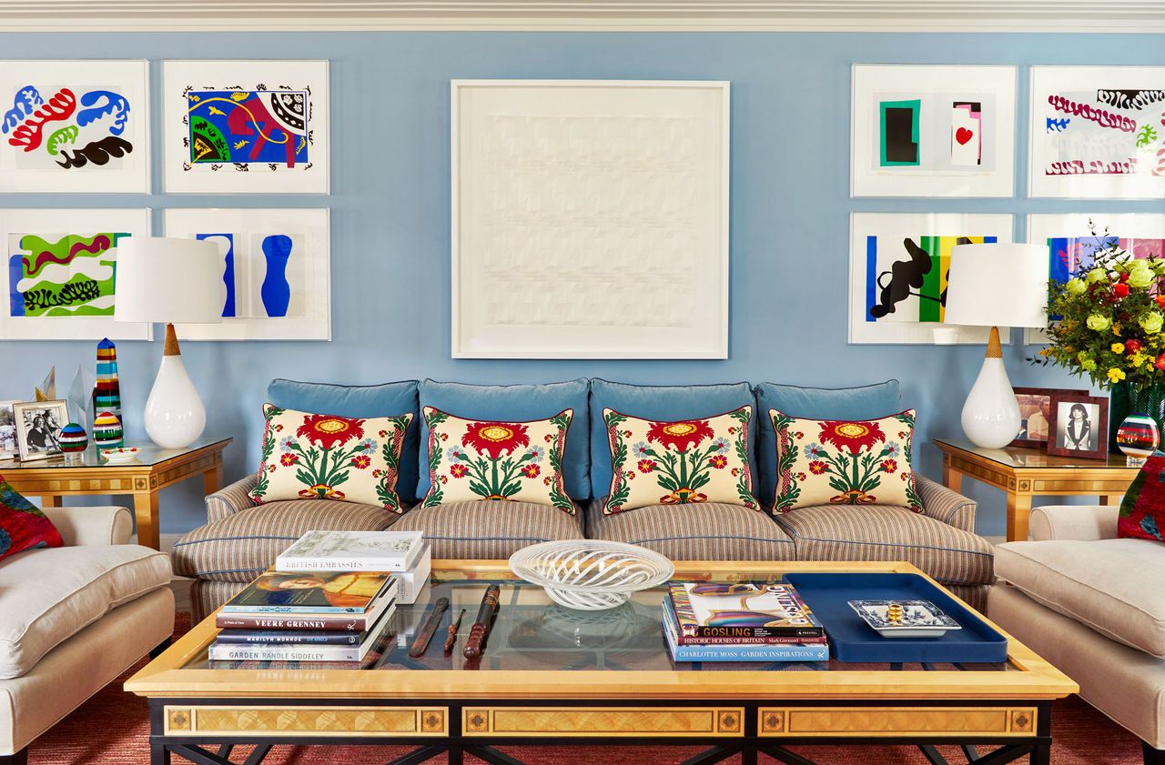 Blue wall with white and blue prints hanging on the walls, blue sofa cushion's