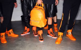 Close up shot of several pairs of orange trainers & an orange bag