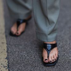 Woman wearing black nail polish and prada sandals GettyImages-1425997030