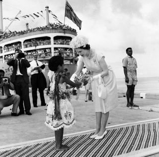 ueen Elizabeth II arrives in Suva, Fiji from the Royal yacht and is presented a bouquet of flowers by Adi Kaunilotuma