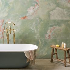 A bath and wooden table against a wall with large onyx tiles