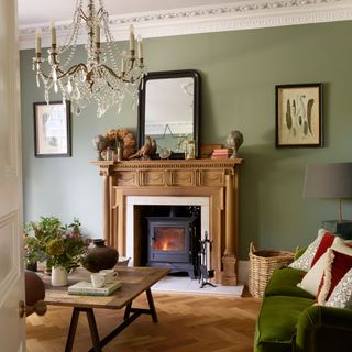 green living room in victorian home with ornate carved mantelpiece, wood burning stove and chandelier