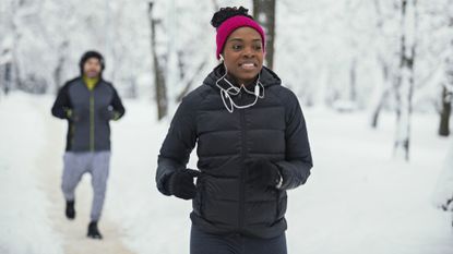 Best winter running gear: pictured here, two people running in cold weather in a forest