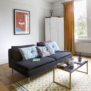 sitting room with white wall and sofa with cushions and curtain on window
