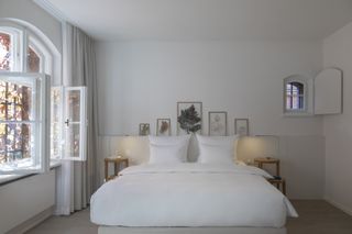 white bedroom with white bedding and framed nature art