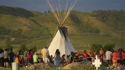 First Nation Canadians gather for a vigil on the site of a burial site in Saskatchewan