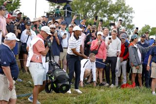 Tiger Woods plays a pitch shot from the spectators