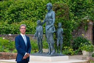 Sculptor Ian Rank-Broadley poses alongside his statue of Diana, Princess of Wales, unveiled by her sons Britain's Prince William, Duke of Cambridge and Britain's Prince Harry, Duke of Sussex, at The Sunken Garden in Kensington Palace, London on July 1, 2021, which would have been her 60th birthday. - The bronze statue depicts the princess surrounded by three children to represent the "universality and generational impact" of her work. Her short cropped hair, style of dress and portrait are based on the final period of her life. Beneath the statue is a plinth engraved with her name and the date of the unveiling, and in front is a paving stone engraved with an extract inspired by The Measure of A Man poem