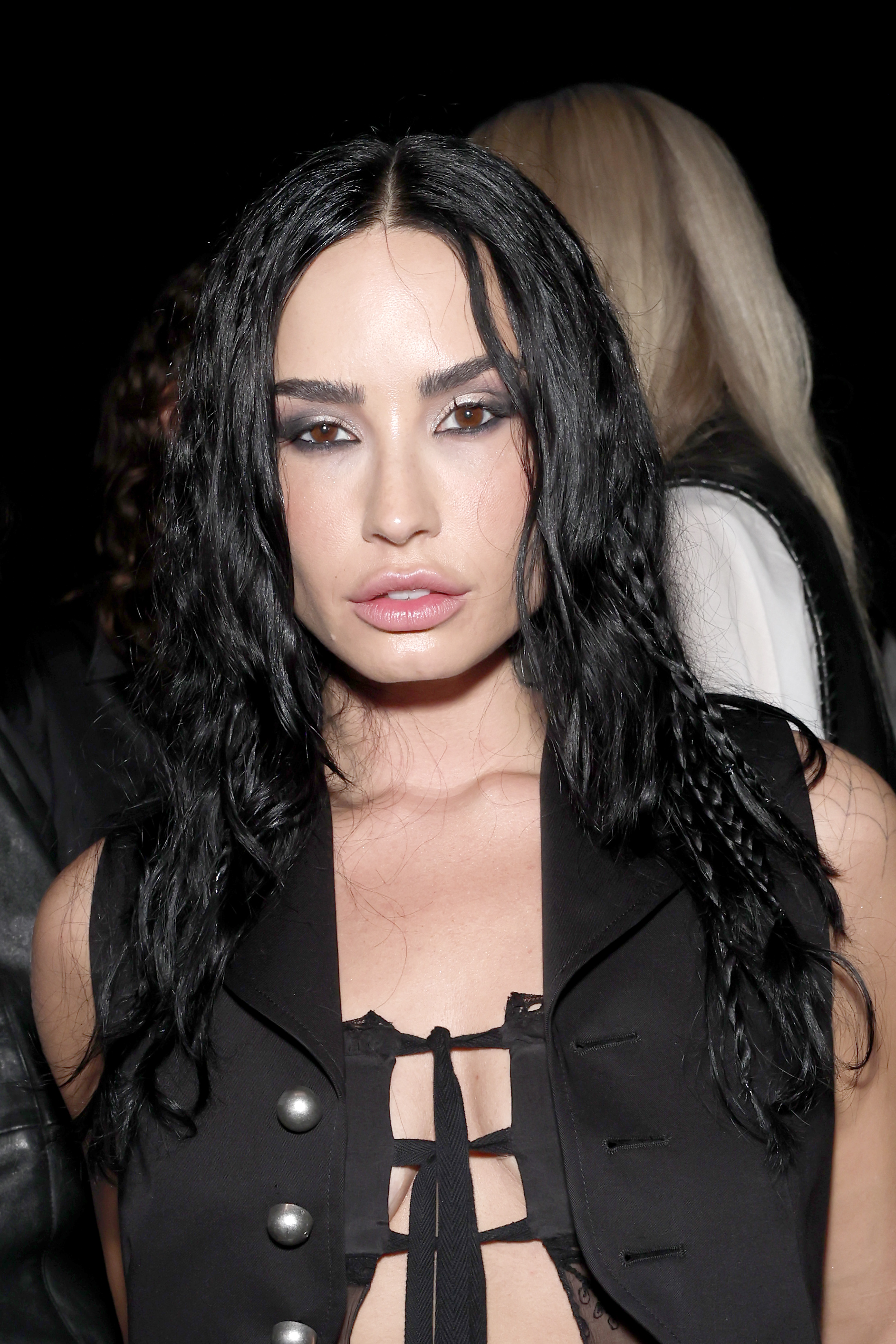 a white woman with brown eyes and black hair wearing a black top and smokey eye makeup