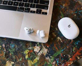 Beats Studio Buds in white resting on silver Macbook laptop