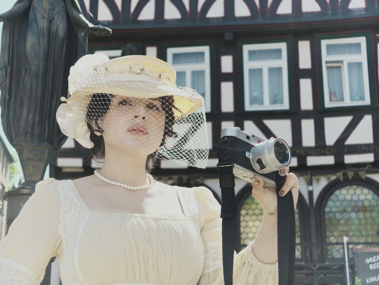 Insta360 Luna Ultra sample gallery: lady in period clothing holding a Leica camera, in quaint German town,