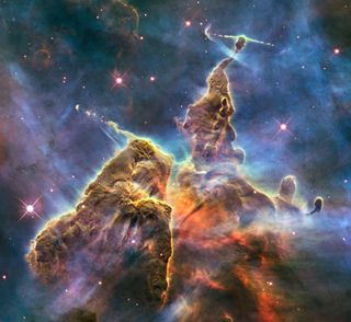 The image captures the top of a three-light-year-tall pillar of gas and dust that is being eaten away by the brilliant light from nearby bright stars. The pillar is also being pushed apart from within, as infant stars buried inside it fire off jets of gas
