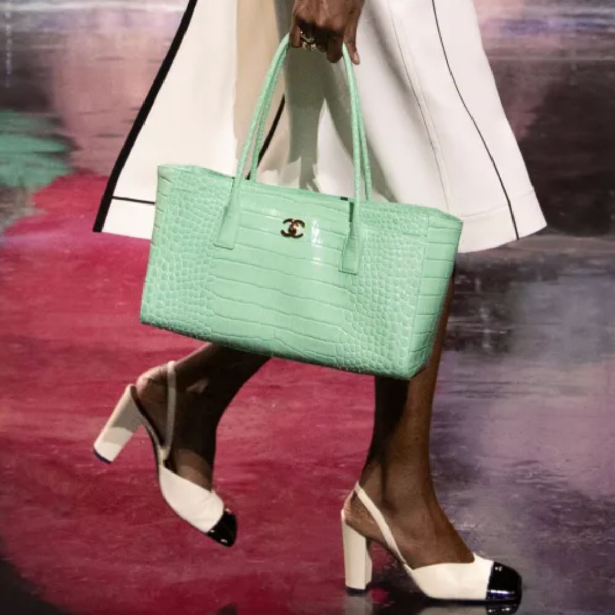 a model at the chanel ss26 show carrying a bag and wearing two-tone heeled shoes