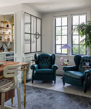 An unused kitchen corner used a a seating nook with jewel green wingback armchairs