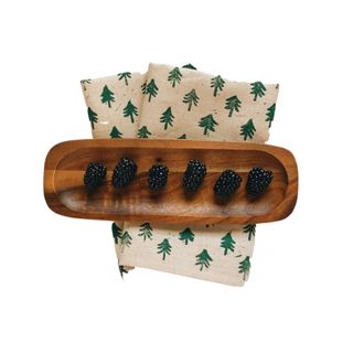 christmas tree napkins with a wooden bowl of blackberries on top