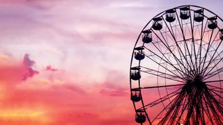 Silhouette of a ferris wheel against a vibrant pink and purple sunset sky, creating a serene and festive atmosphere