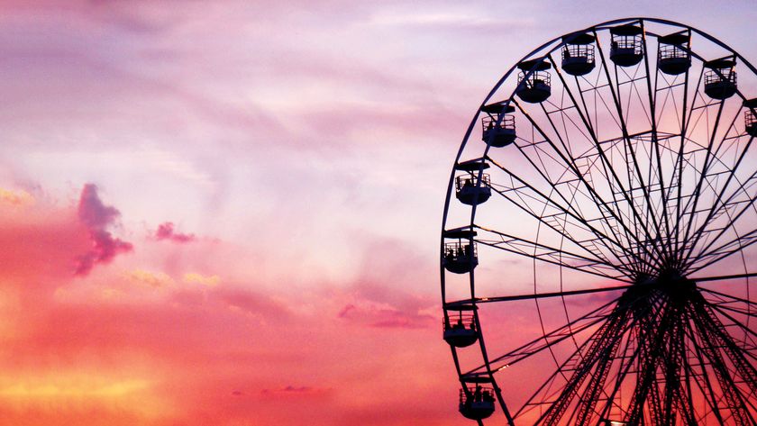 Silhouette of a ferris wheel against a vibrant pink and purple sunset sky, creating a serene and festive atmosphere
