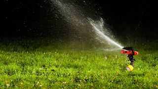 sprinkler watering lawn at night
