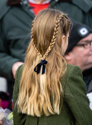 The back of Princess Charlotte's head showing a braided hairstyle with a blue velvet bow