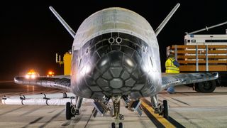 a head-on photograph of the X-37B space plane on a runway at night