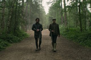 Joe and Roald holding rifles as they walk through the woods
