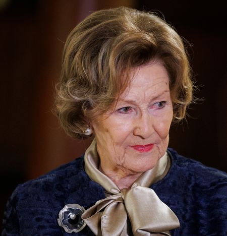 A headshot of Queen Sonja of Norway wearing a blue jacket and tie-neck blouse