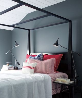 bedroom with gray wall, white ceiling and black four poster bed with red and white bedding