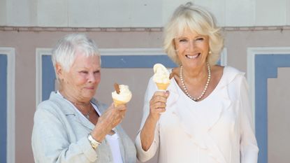 Camilla, Duchess of Cornwall enjoys an ice cream with Dame Judi Dench as she arrives at Queen Victoria's private beach, next to the monarch's holiday home, during her visit to the Isle of Wight on July 24, 2018 in Cowes, Isle of Wight, United Kingdom.