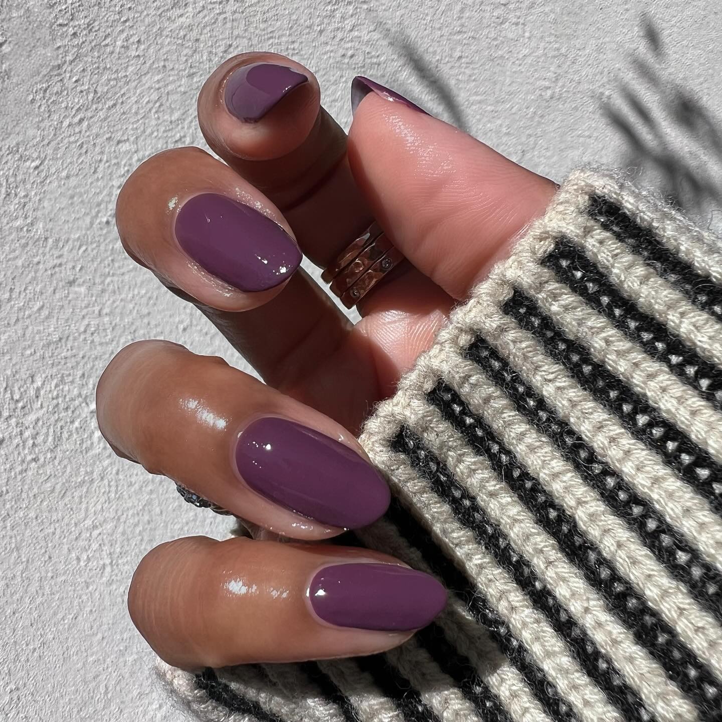 A close-up shot of a purple, almond-shaped manicure