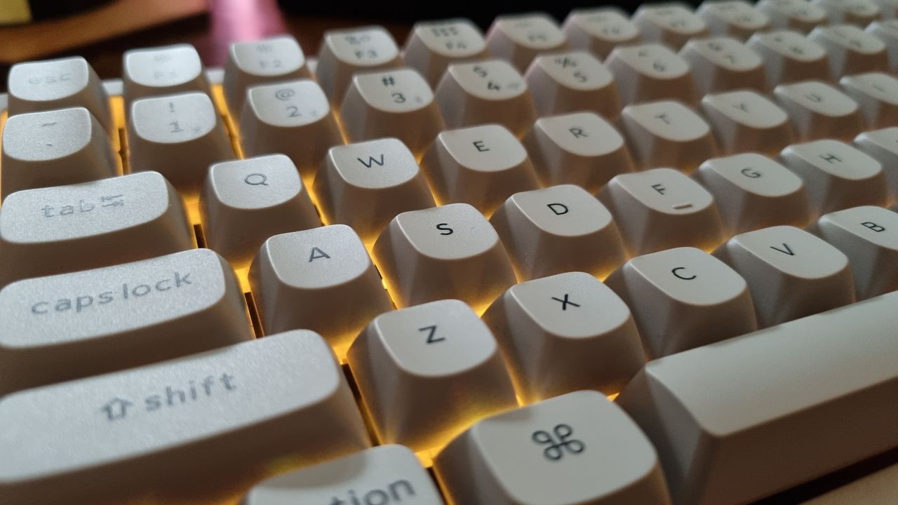 Various angles of a Keychron K2 HE Concrete Edition keyboard lit up in RGB lighting