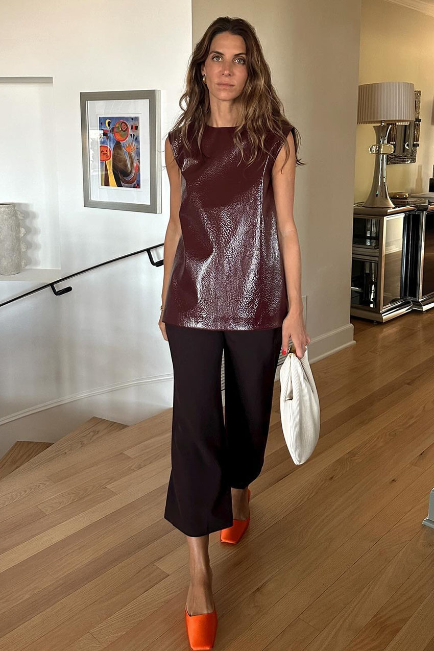 A woman wearing a burgundy leather top with burgundy culottes and orange flats