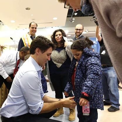 Prime Minister Justin Trudeau helps Syrian refugees find winter coats after landing in Canada