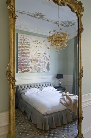 A large gilded mirror opposite the bed