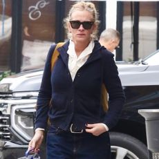 Julia Roberts walks down the street wearing dark-wash jeans with white ballet flats.