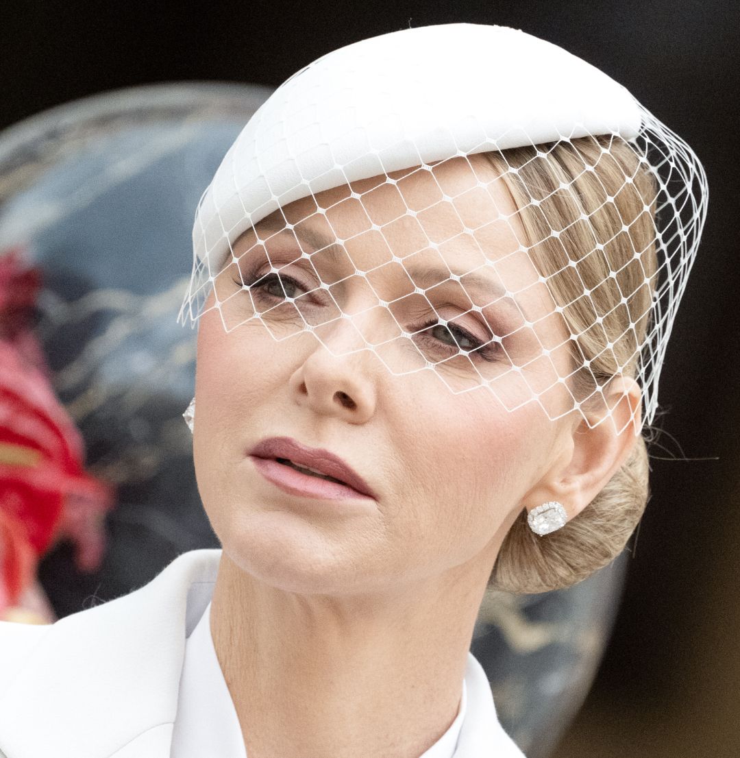Princess Charlene wearing a white veiled hat and white suit