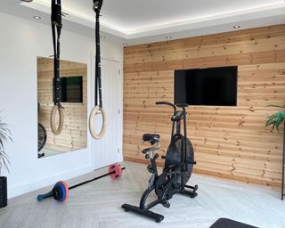 home gym with wood flooring, TV and wall panelling - Sophie McNally