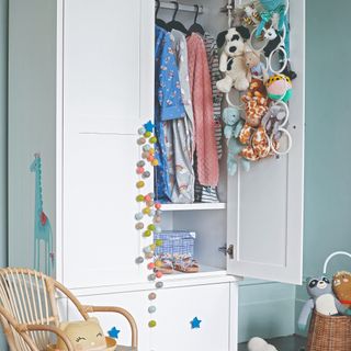 A blue kids' room with a white wardrobe with a drawer on the bottom