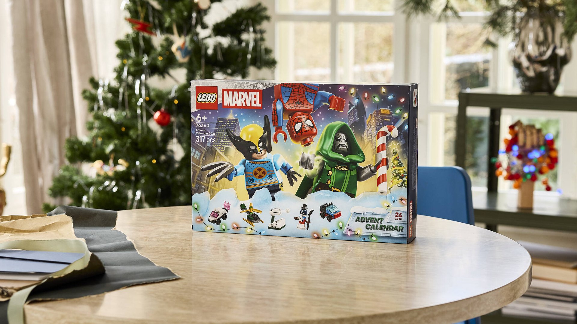 Lego Marvel Advent Calendar box on a wooden table, in front of a Christmas tree