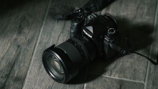 The Pentax 24-70mm f/2.8 on a gray wood texture background