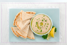 A plate of hummus with pitta bread on a blue background 
