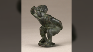a small Roman bronze statuette of a man squatting while making fart noises with his mouth