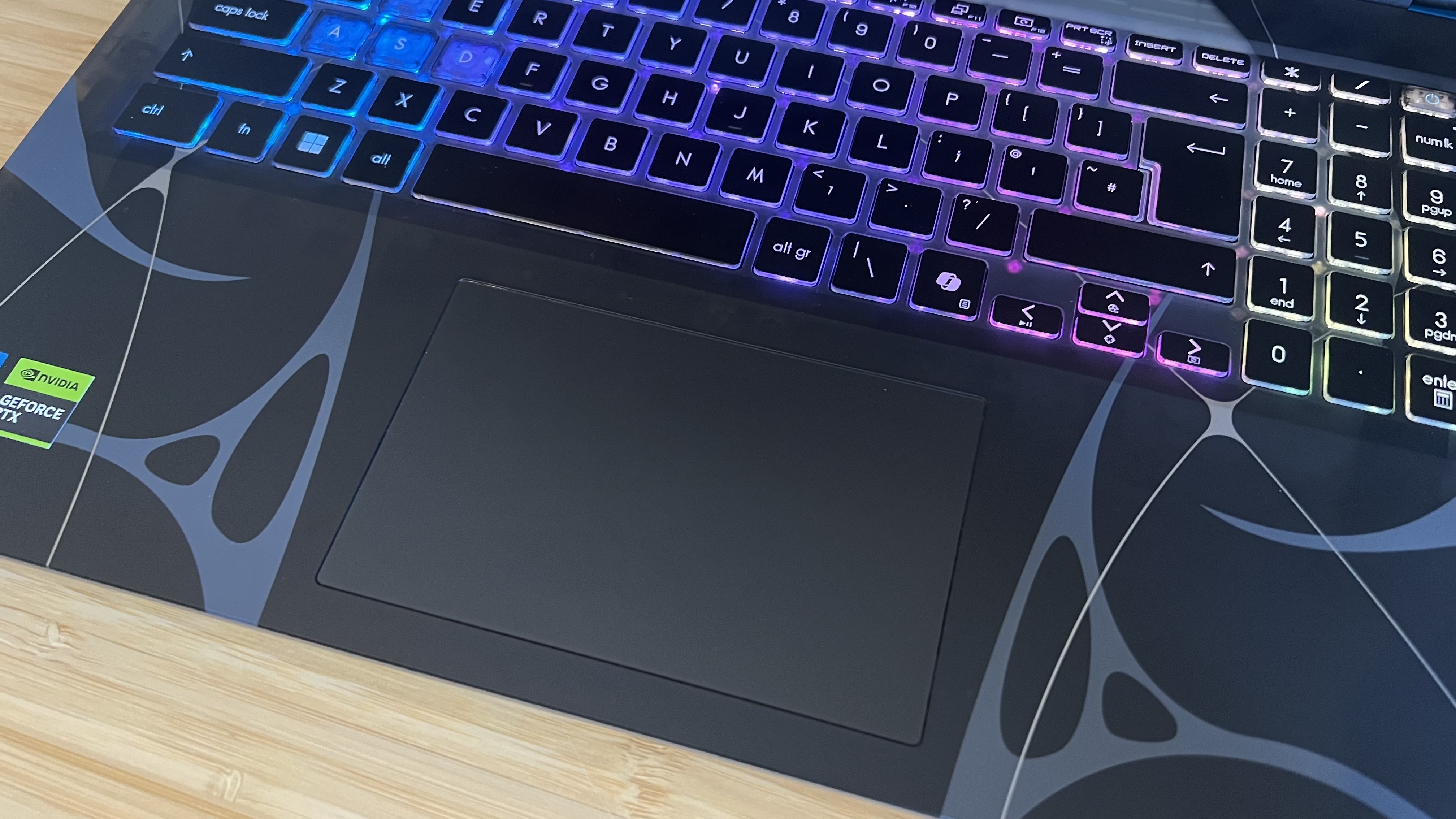 Close up on trackpad of MSI Cyborg gaming laptop on a wooden desk