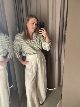 Woman wears green striped shirt and white wide leg trousers