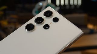 En närbild på kameramodulen på baksidan av en vit Samsung Galaxy S23 Ultra.