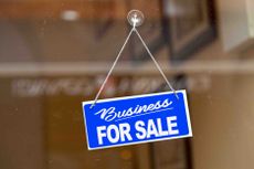 a business for sale sign hanging in a window